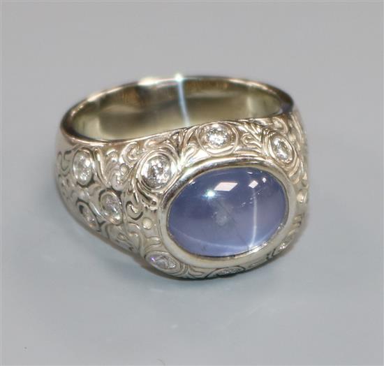 An ornate white metal, cabochon star sapphire and diamond set dress ring, size Q/R.